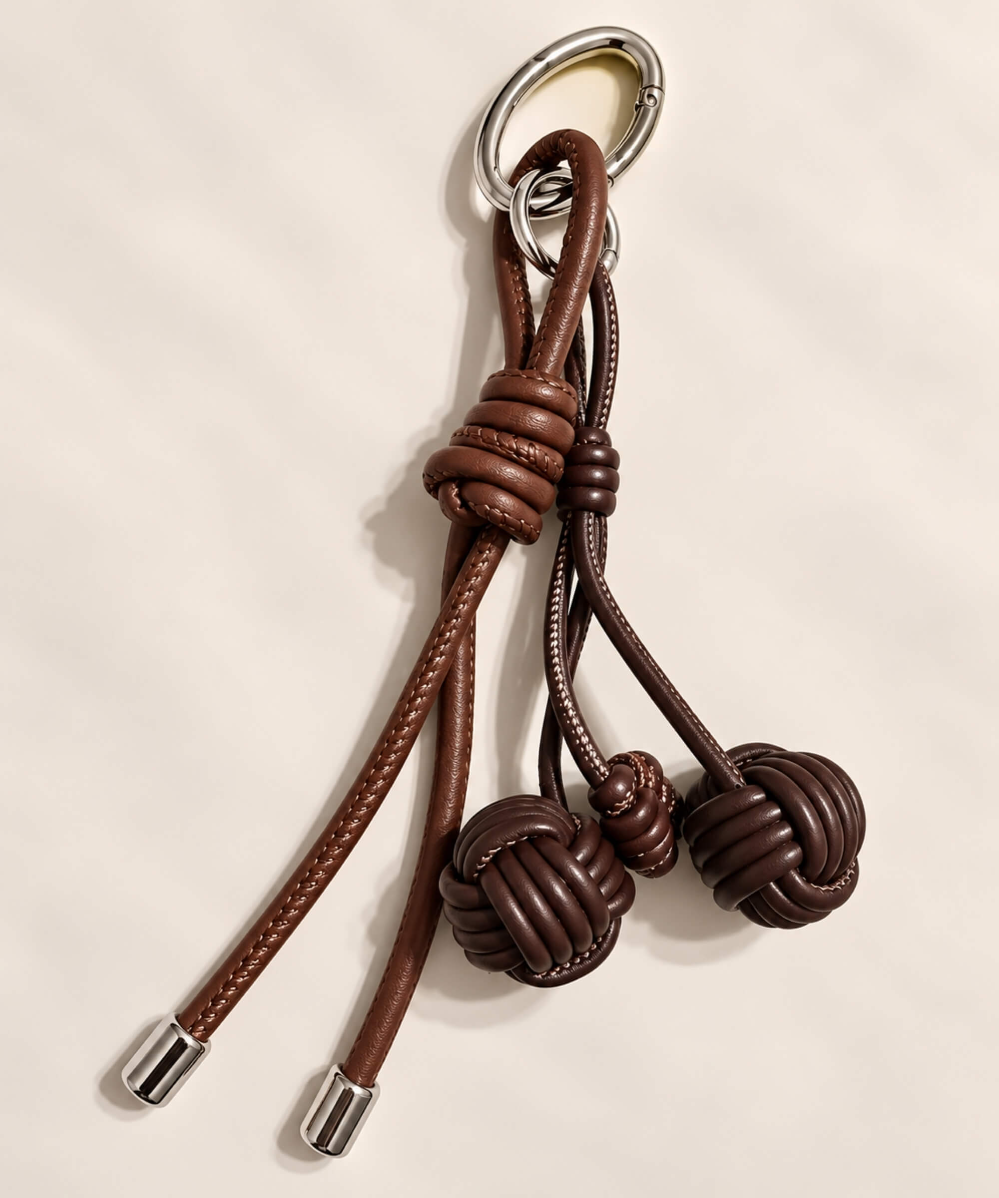 Close-up of brown knotted ball PU leather bag charm with long cord details
